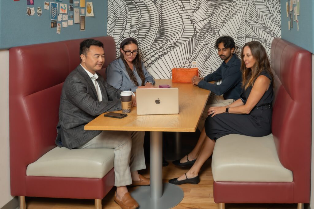 OG Advisors – Booth Working Session Sean Zeng, Alexandria Schraibman, Suraj Srinivasan and Daniela Matson of OG Advisors meeting in a booth