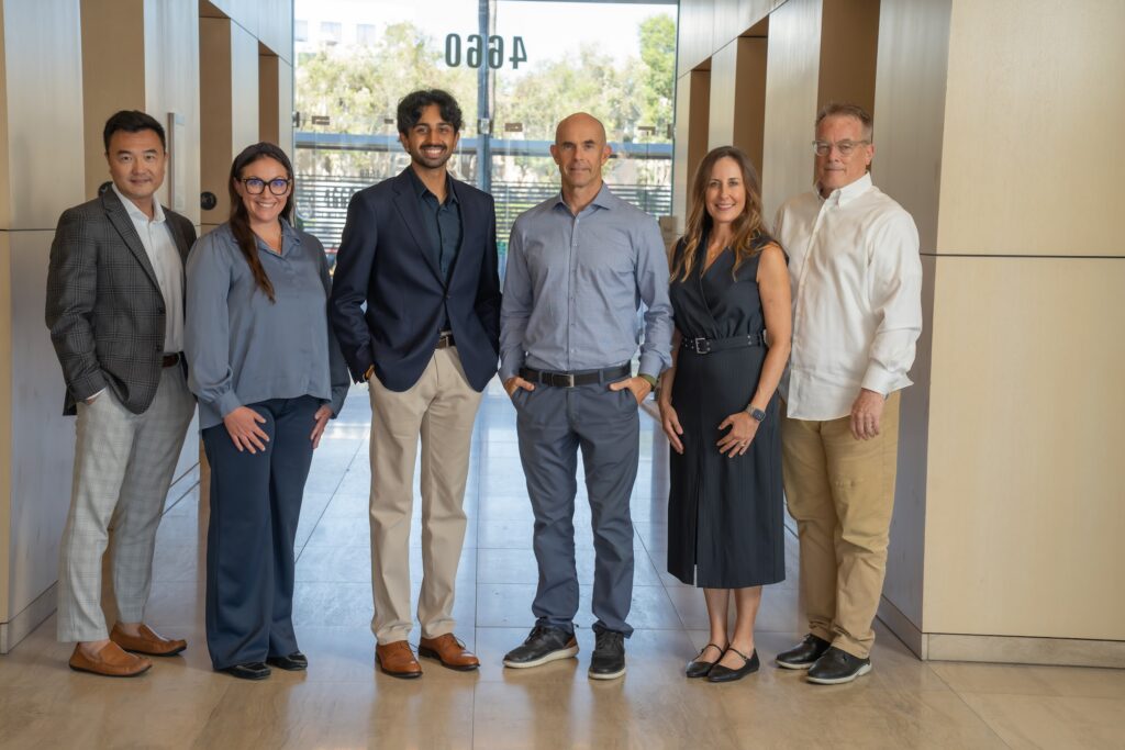 OG Advisors Team – Lobby Group Portrait The six-person OG Advisors team standing in a bright building lobby